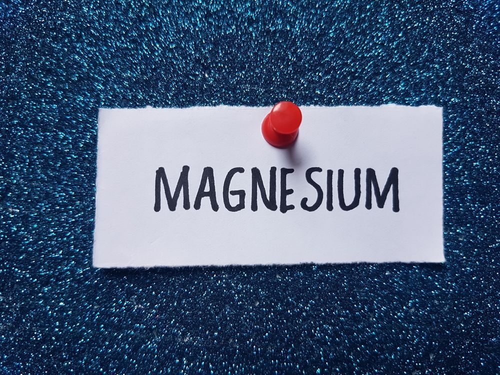 A piece of paper with the word magnesium written on it is pinned to a blue background.