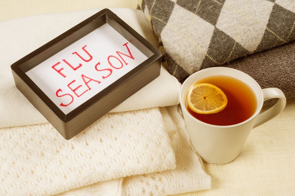 A cup of tea with a slice of lemon next to a sign that says flu season