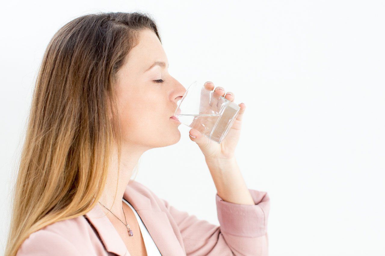 A woman is drinking a glass of water.