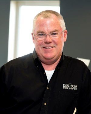 A man wearing glasses and a black shirt with the word don on it | Don & Sons Body Shop