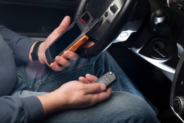 Two hands holding smartphones while seated in a car interior