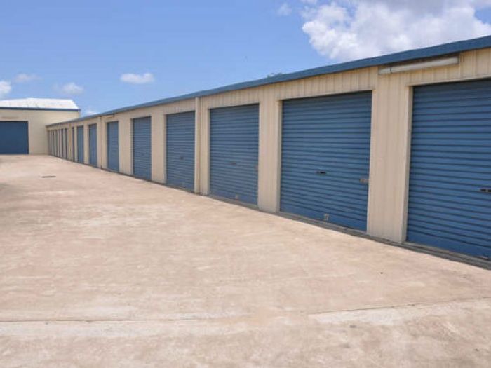Row of beige and blue storage units under a blue sky.