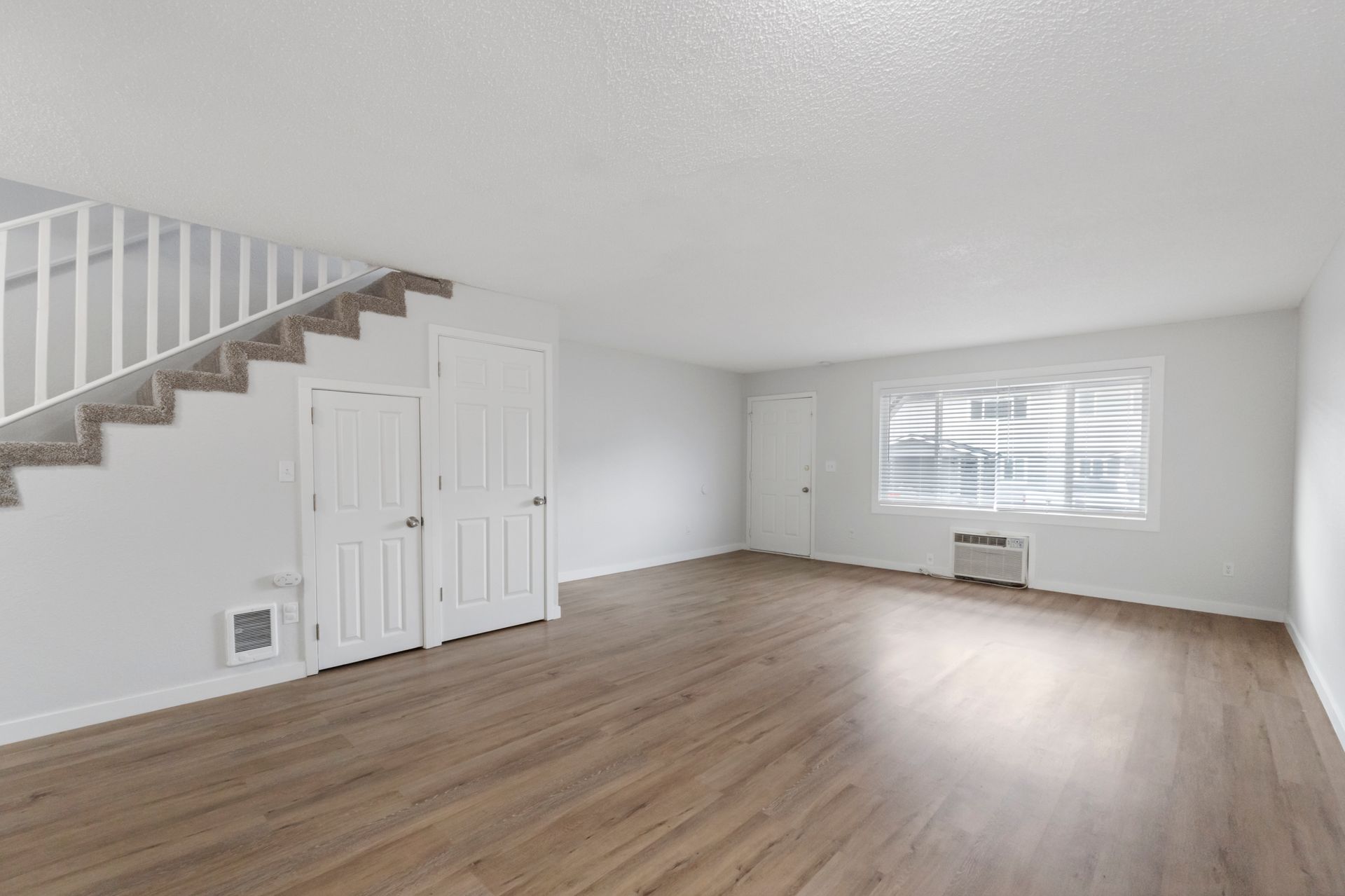 An empty living room with hardwood floors and stairs.