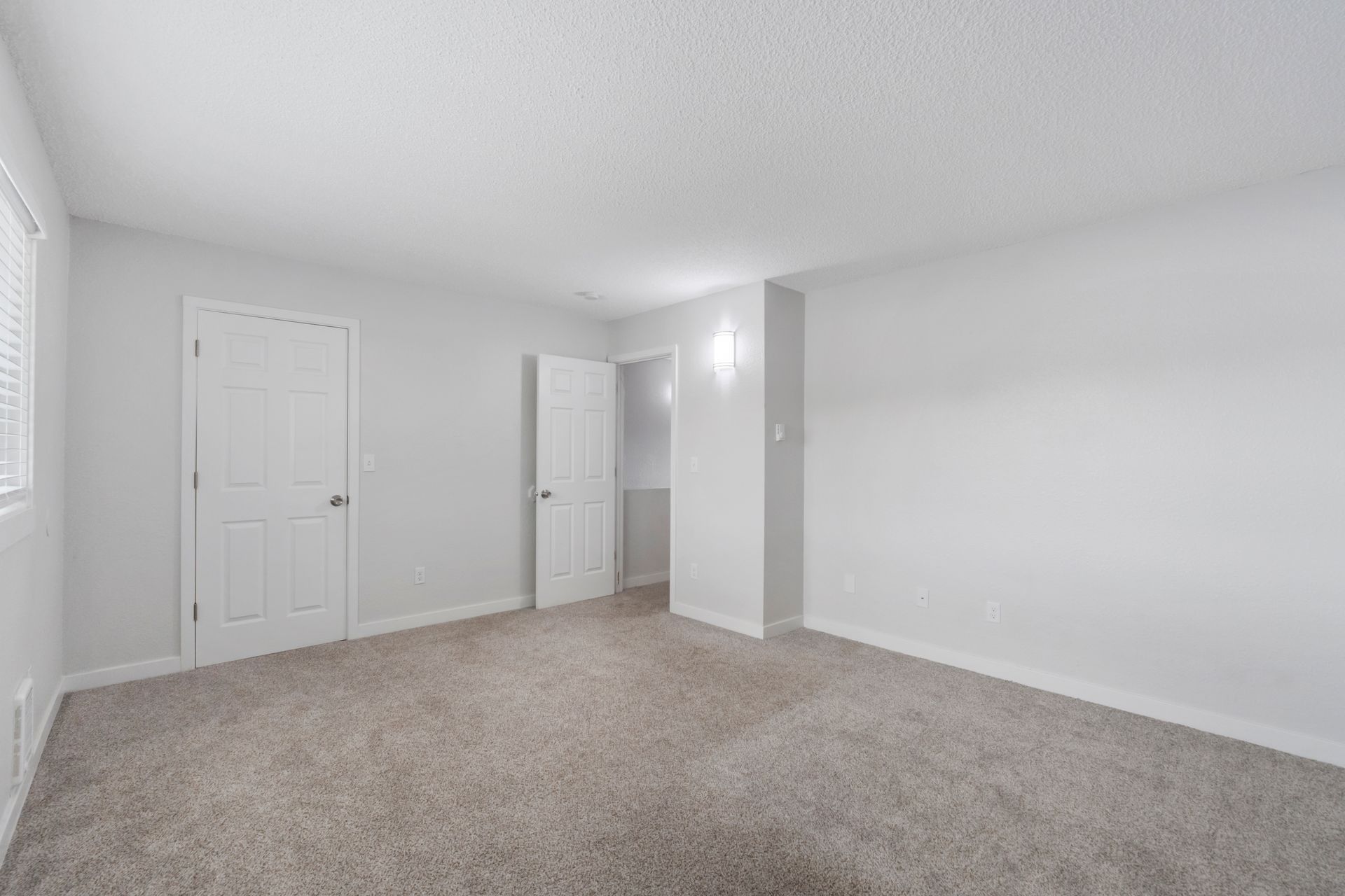 An empty bedroom with a carpeted floor and white walls.