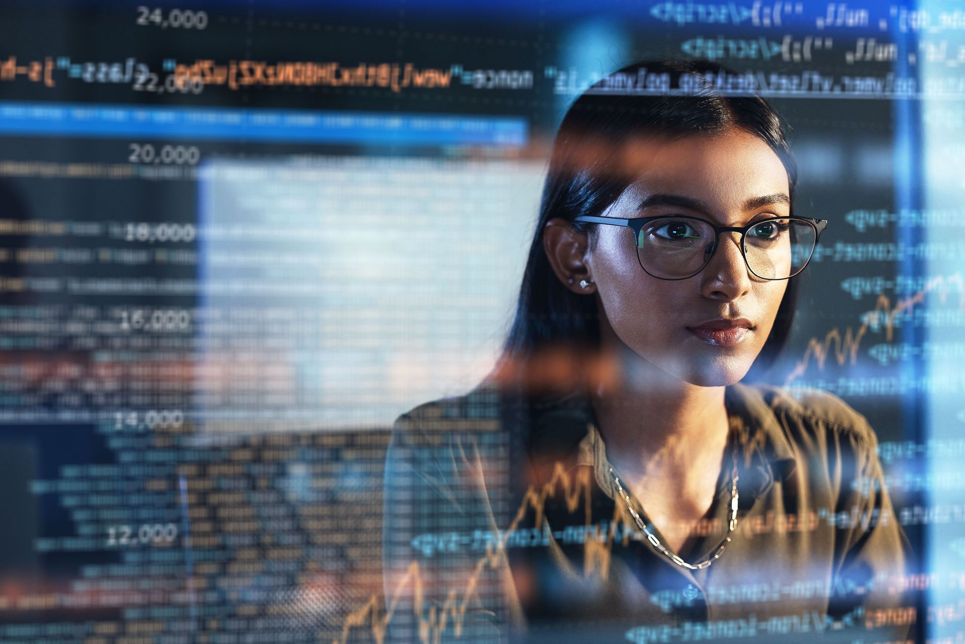 Woman wearing glasses looking at computer screen with code.