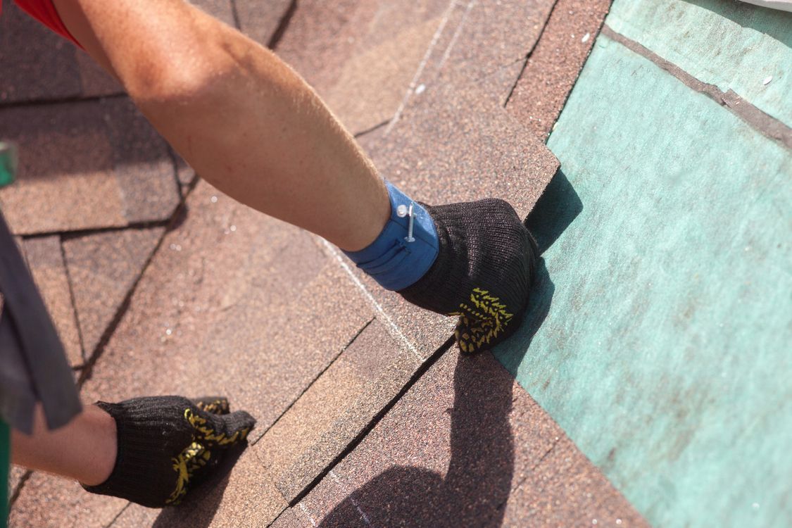 Person climbing a steep roof, wearing black shoes with yellow grips and a blue sock visible.