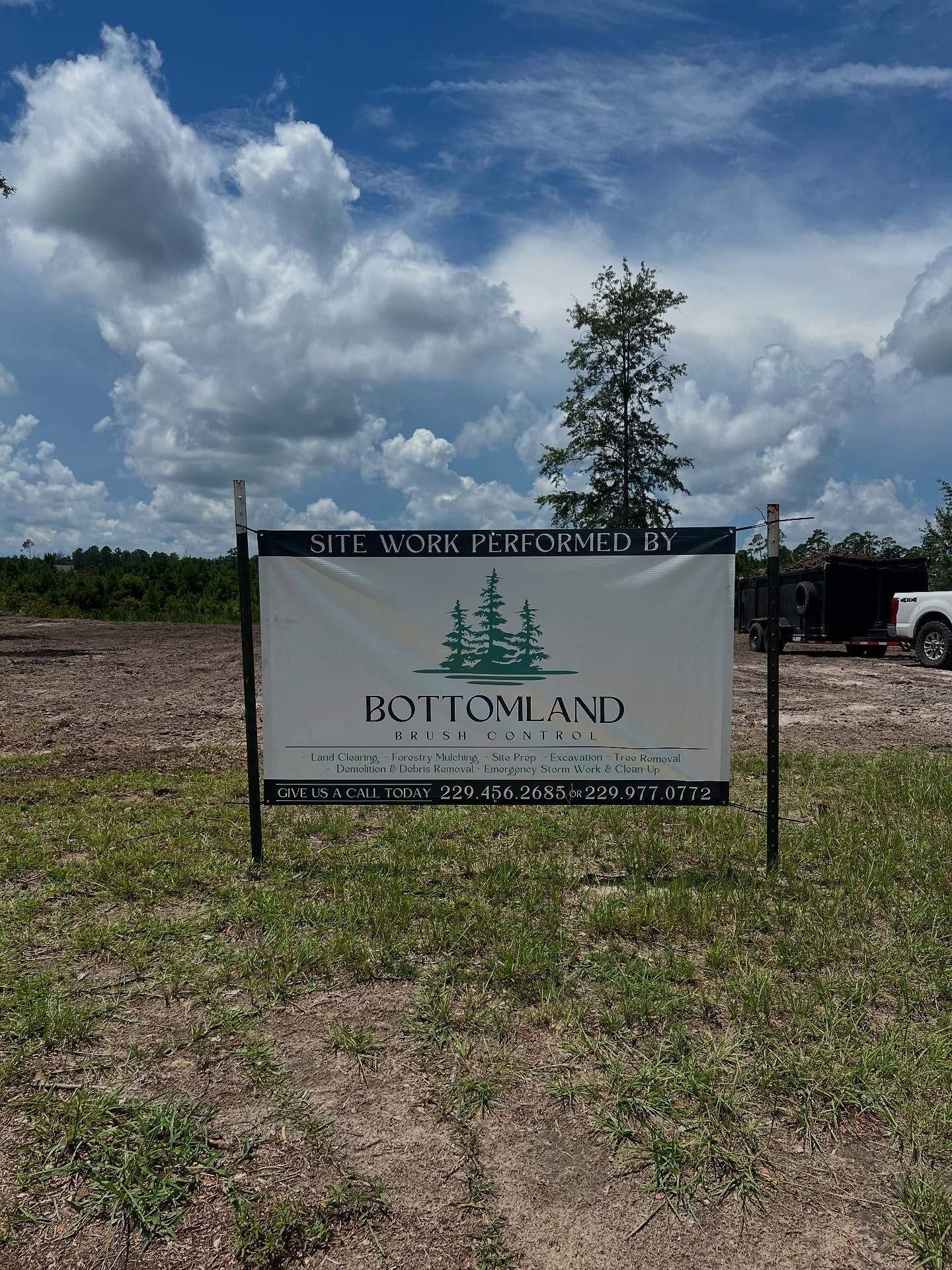 Sign for Bottomland field against a cloudy blue sky, surrounded by a rural dirt landscape.