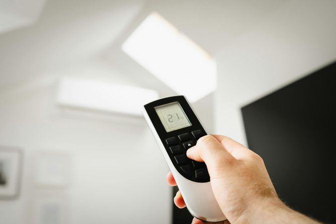 An electrician inspects an open residential electrical service panel mounted on a wall inside a garage.