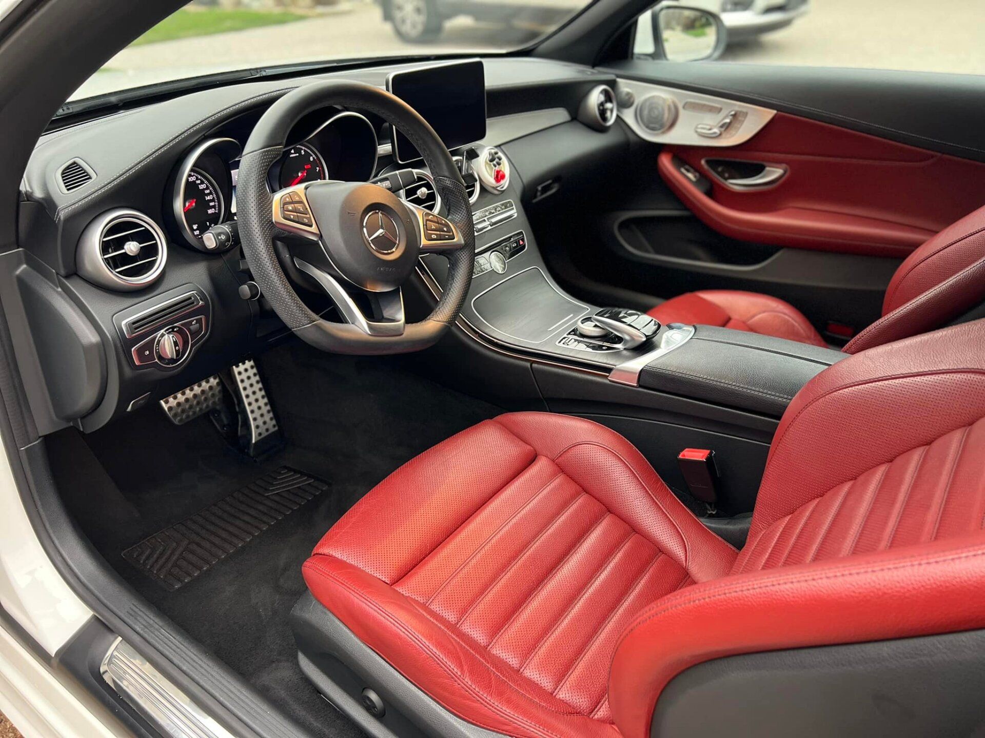 The interior of a white car with red seats and a steering wheel.