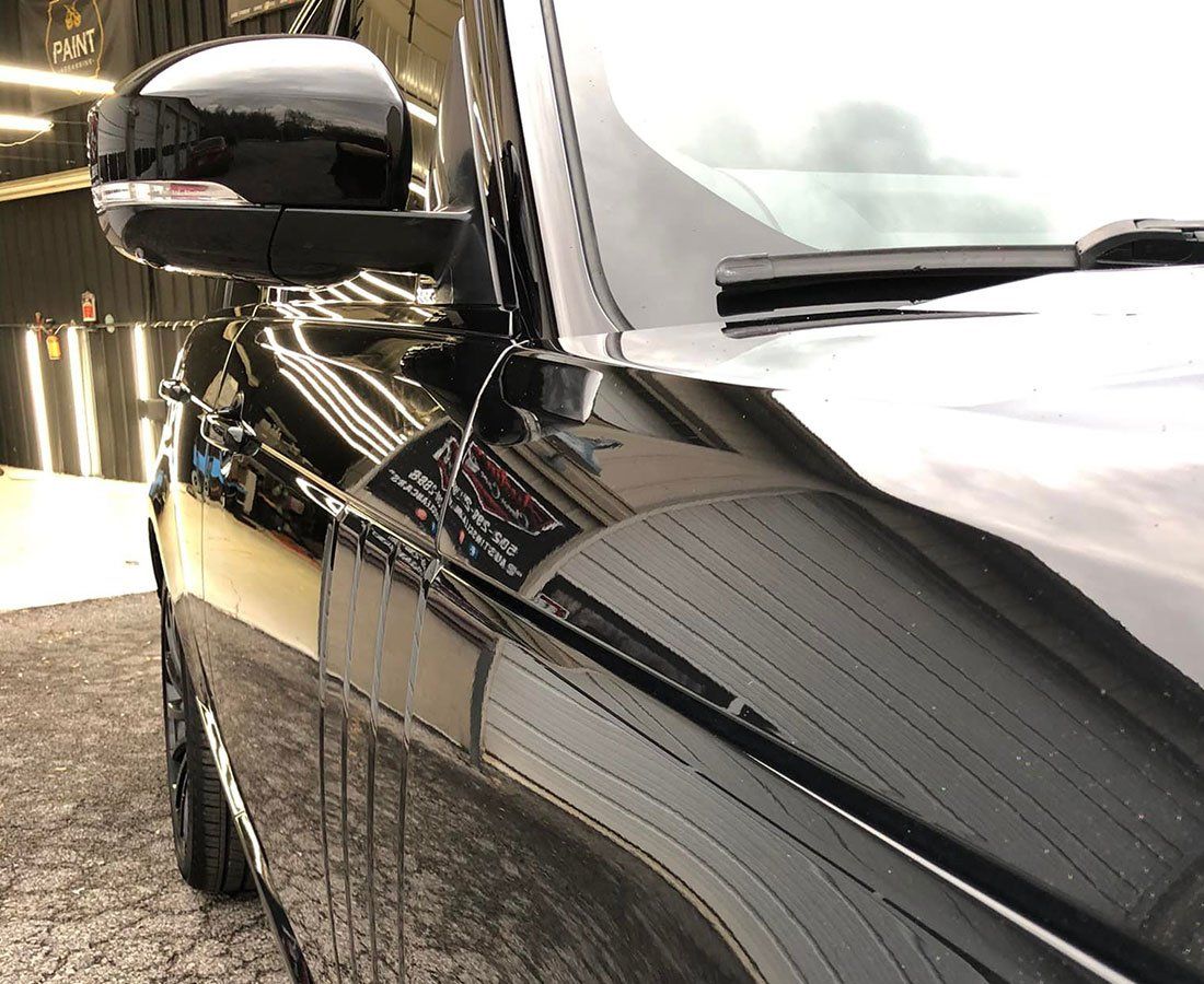 A close up of a black car parked in a parking lot.
