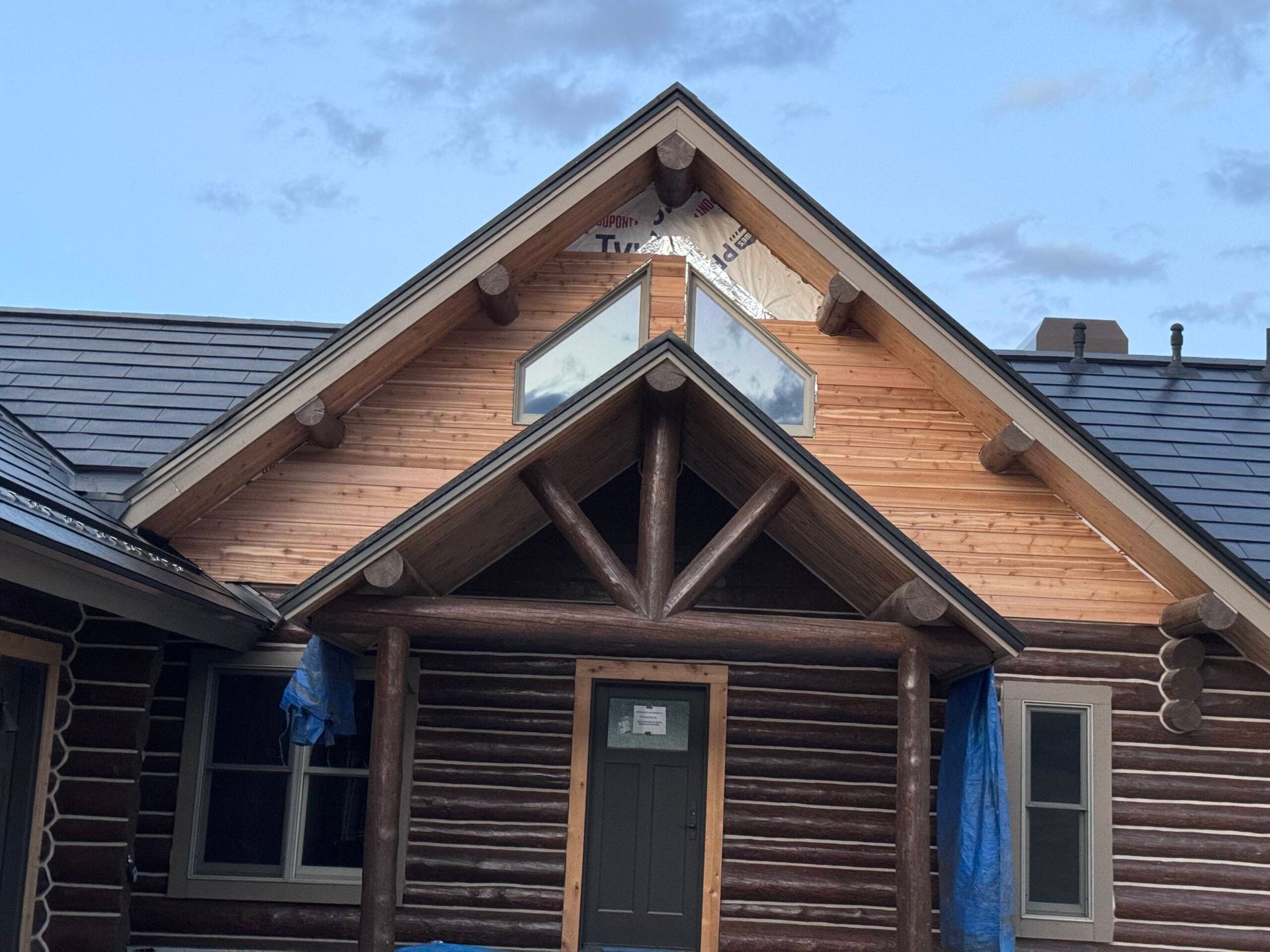 Wooden log cabin front entrance with a gabled roof and small porch under construction