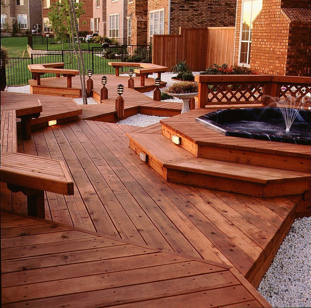 Curved wooden deck and benches around a brick patio fountain in an outdoor courtyard