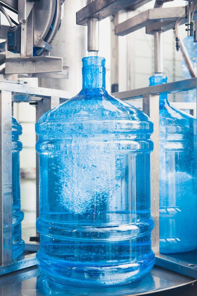 A Large Bottle Of Water Is Being Filled In A Factory — Eureka Water & Filtration In Mackay, QLD