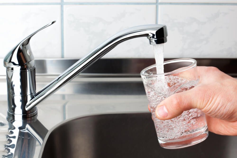 A Person Is Pouring Water Into A Glass From A Faucet — Eureka Water & Filtration In Mackay, QLD