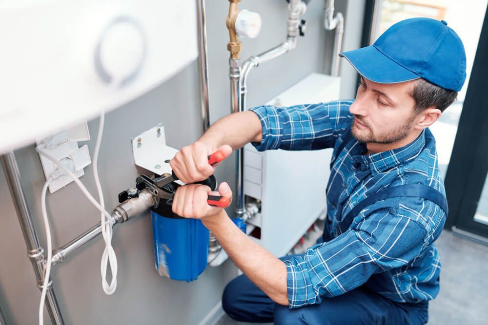 A Plumber Is Working On A Water Filter In A Bathroom — Eureka Water & Filtration In Mackay, QLD
