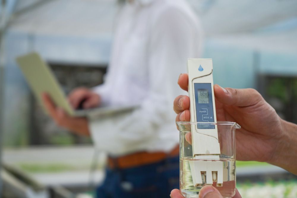 A Person Is Holding A Thermometer Over A Glass Of Water — Eureka Water & Filtration In Mount St John, QLD