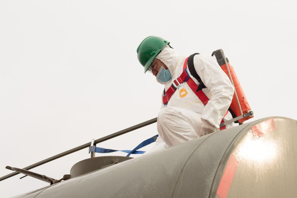 A Man In A Protective Suit And Helmet Is Standing On Top Of A Tank — Eureka Water & Filtration In Mount St John, QLD