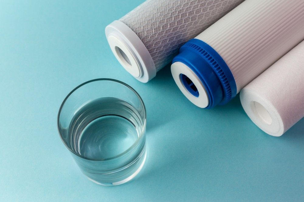 Three Water Filters And A Glass Of Water On A Blue Surface — Eureka Water & Filtration In Mackay, QLD