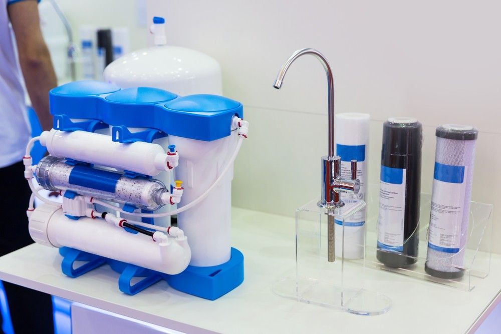 A Water Filter Is Sitting On A Table Next To A Faucet — Eureka Water & Filtration In Mount Isa, QLD