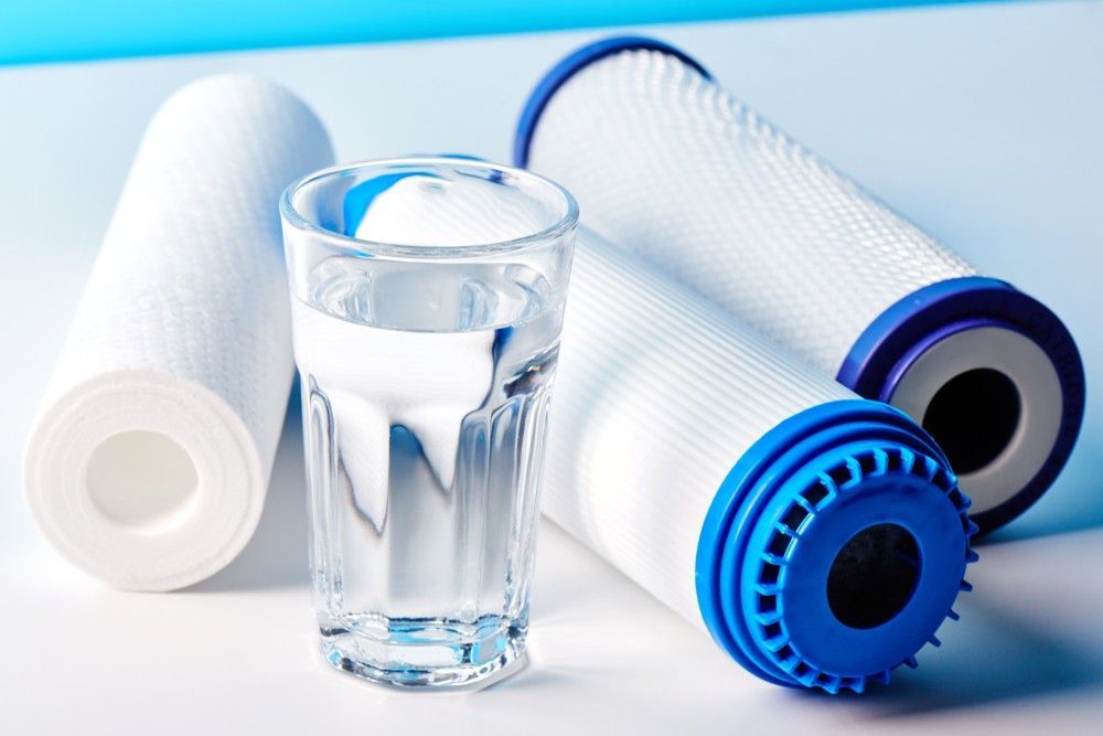 A Glass Of Water Surrounded By Water Filters On A Table — Eureka Water & Filtration In Cairns, QLD