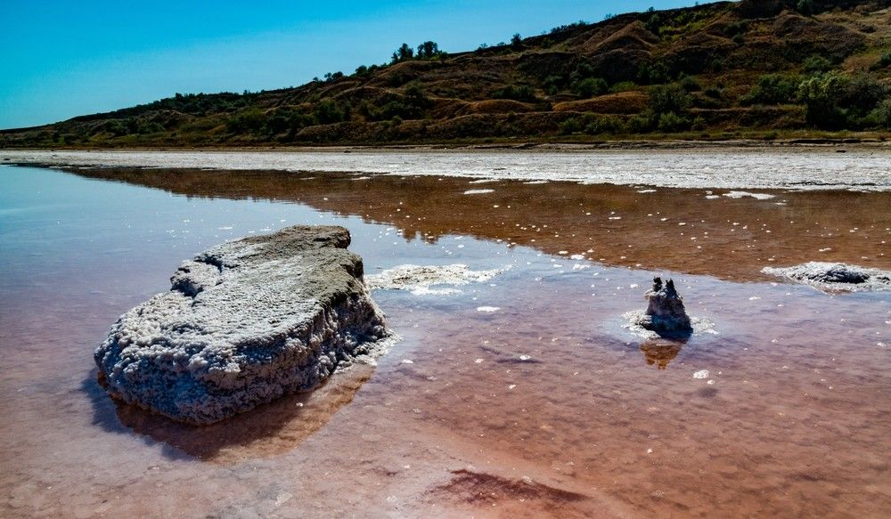 A Large Rock Is Sitting On The Shore Of A Lake — Eureka Water & Filtration In Cairns, QLD