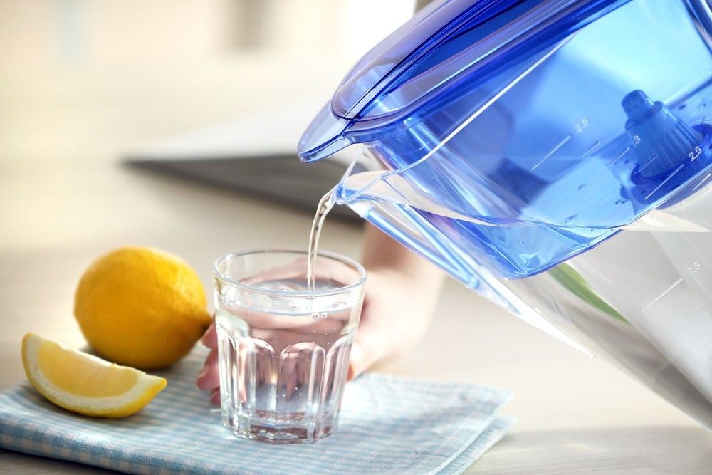 A Person Is Pouring Water From A Pitcher Into A Glass — Eureka Water & Filtration In Mount Isa, QLD