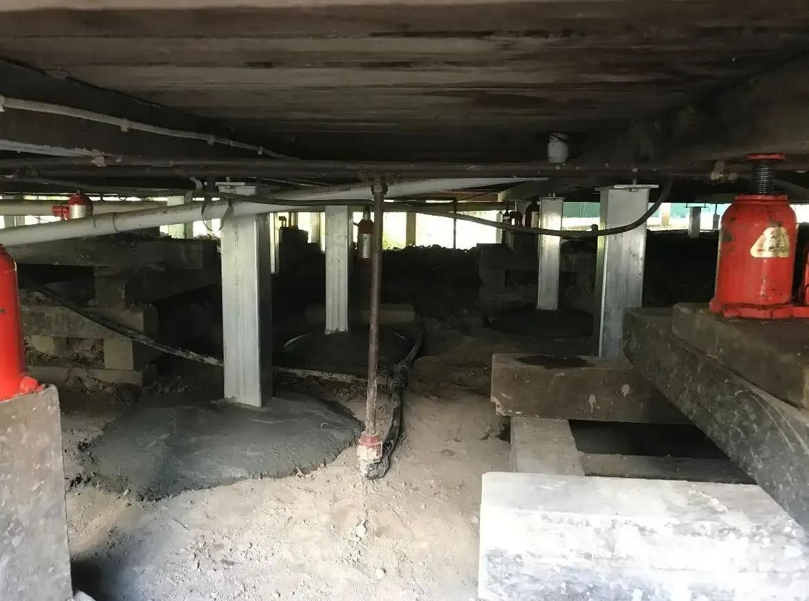 A Red Bottle Jack is Sitting Under a Wooden Floor — Wilson's House Restumping in Northern Rivers, NSW