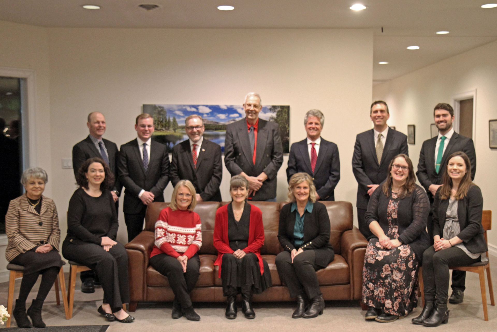 Group portrait of twelve people in formal attire posing in a conference room