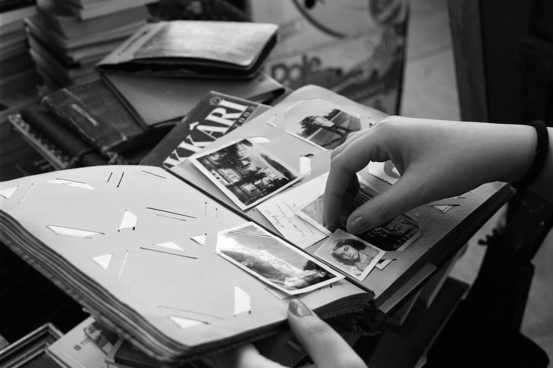 Hand flipping through a stack of magazines on a cluttered desk in black and white