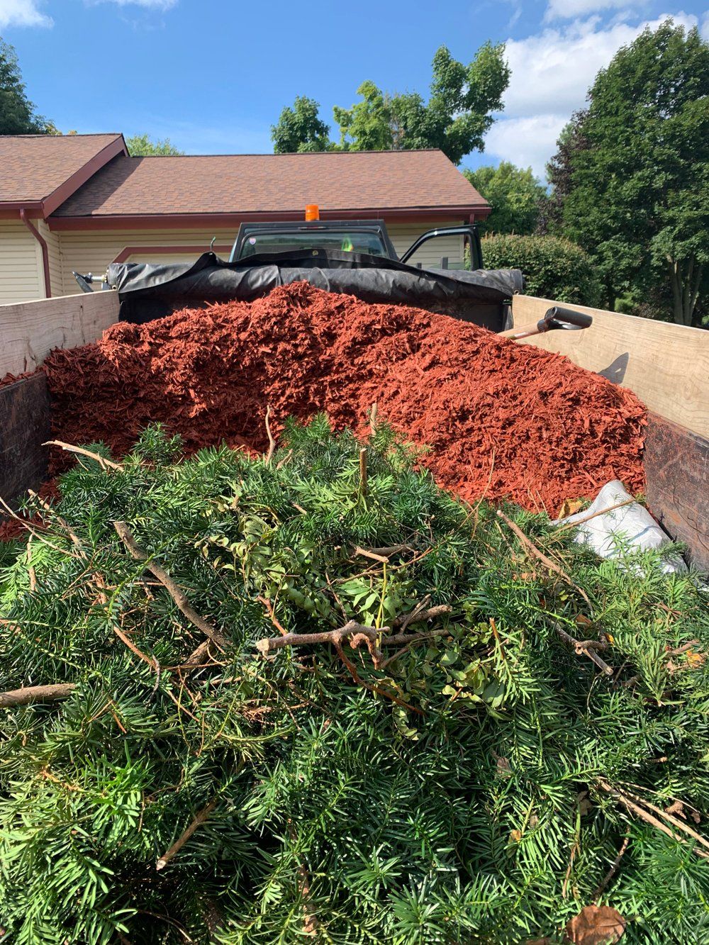 A wooden deck with stairs leading up to it is in the backyard of a house. mulch installation