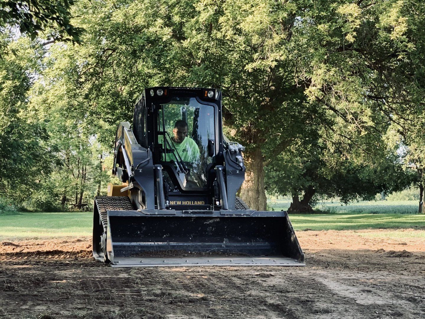 A man is driving a bulldozer in a park. SOD AND TURF