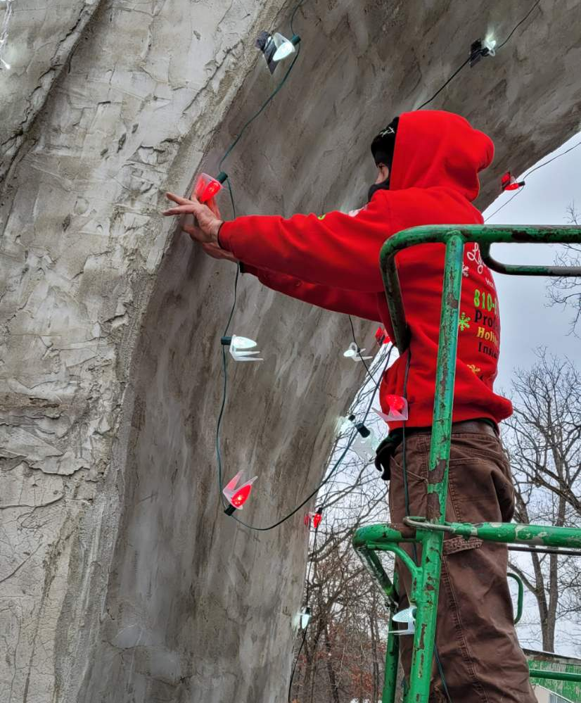 Certified and trained aerial lift operator from light up your life holiday lights installing lights on a commercial castle building. 