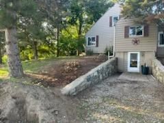 A house with a stone wall and a driveway in front of it.