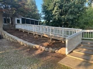 A white ramp leading to a house with stairs leading up to it.