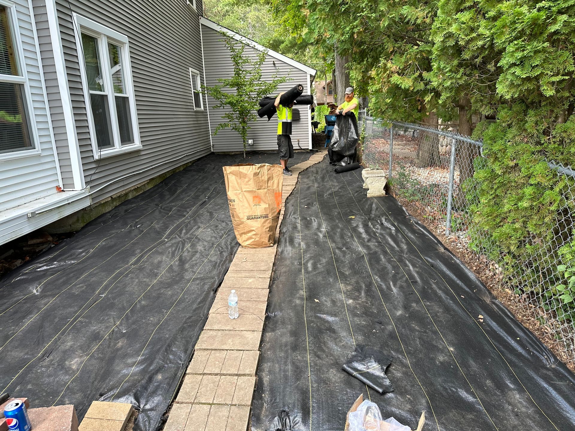A brick wall is being built in front of a house. landscape fabric