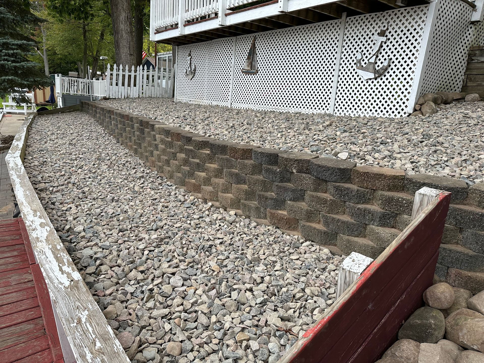 A path leading to a house surrounded by rocks and a chain link fence. rock install