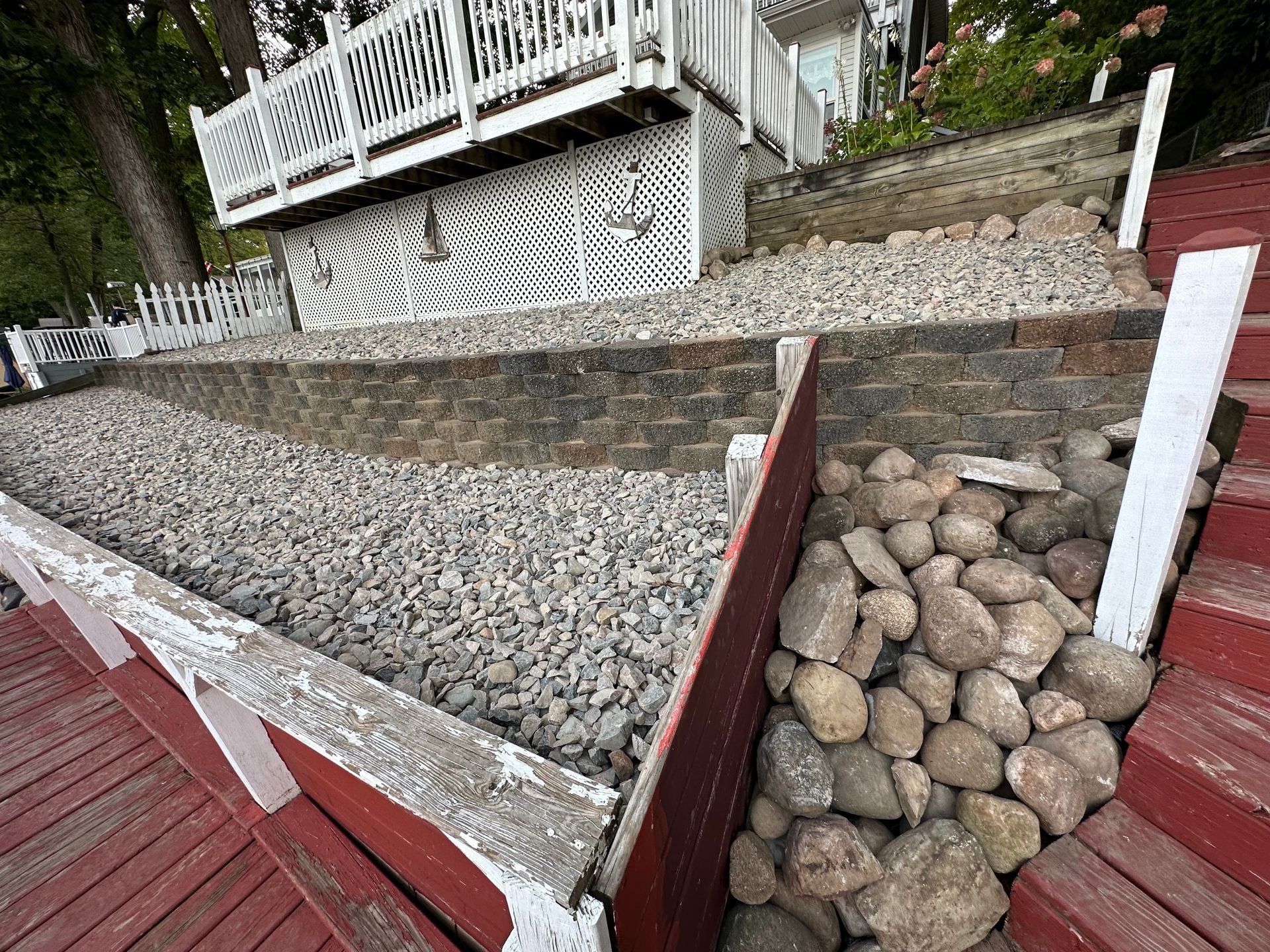 A pile of rocks is sitting on a wooden deck next to a house. landscape