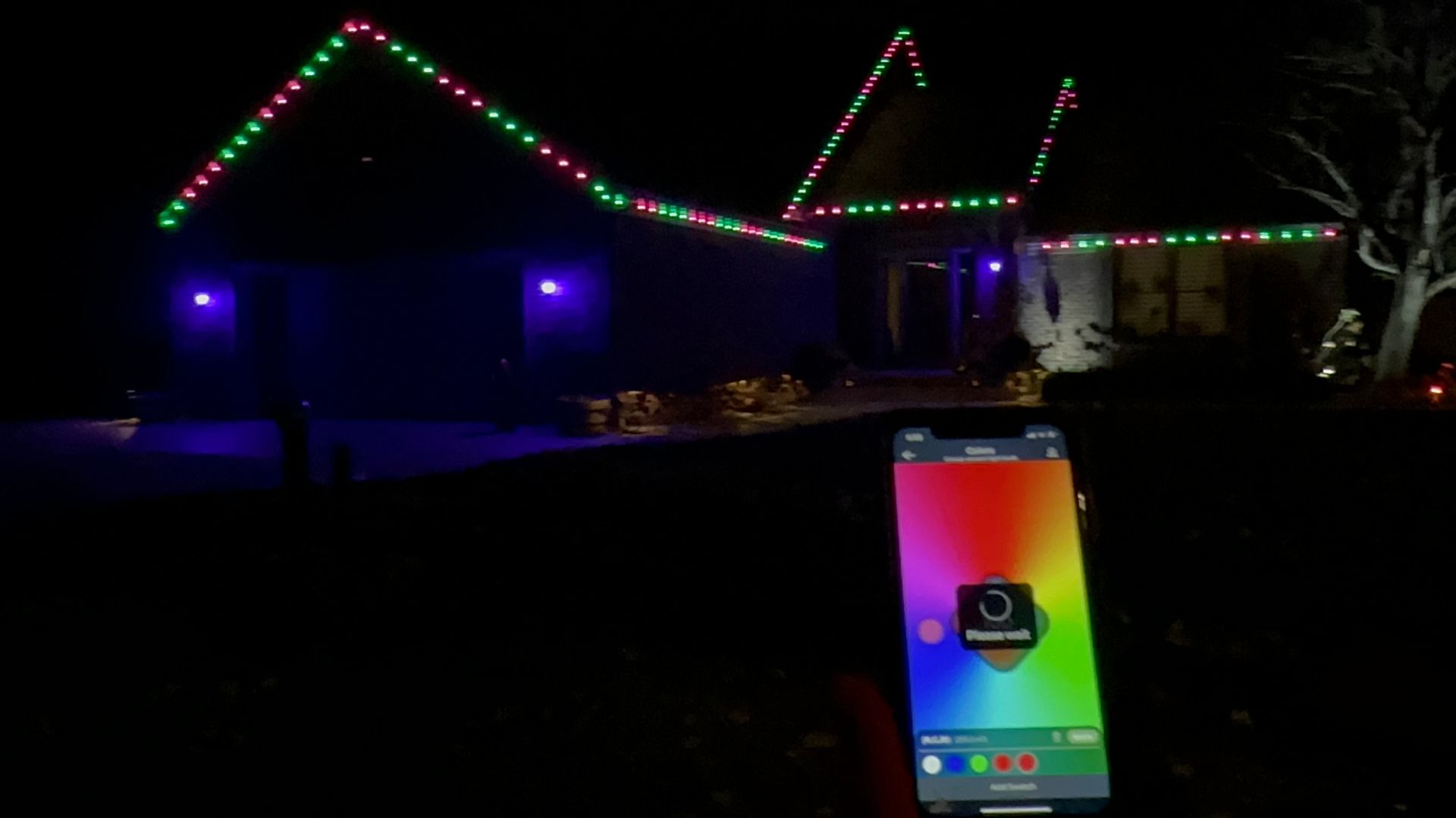 Commercial grade permanent lighting on a residential home in davison michigan. pink and green colors on roofline. Showing a phone that controls the colors from an app that light up your life holiday lights trains clients on how to use. 