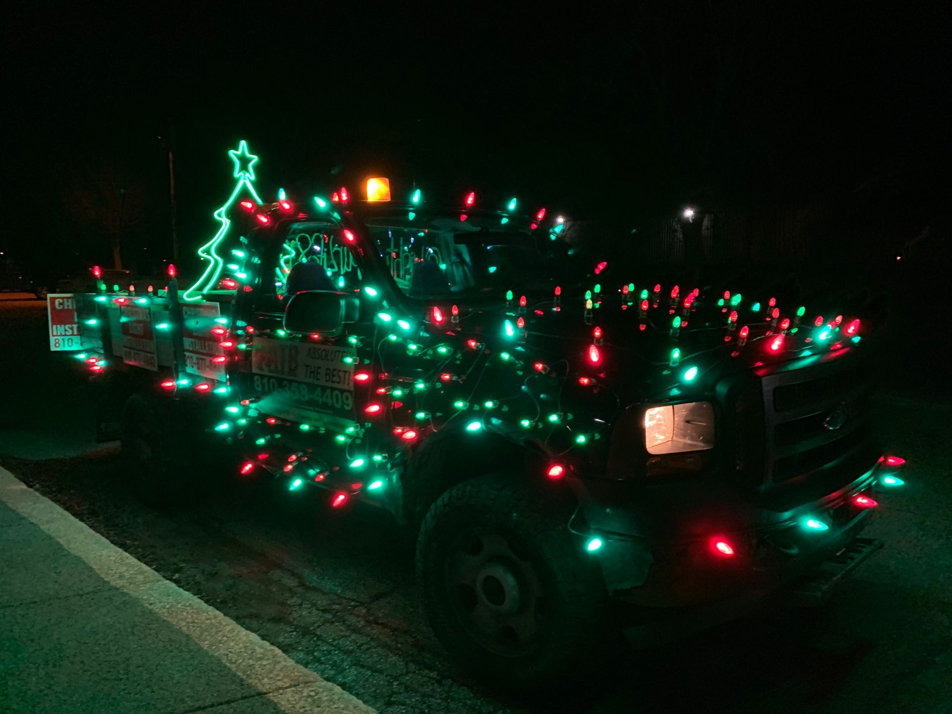 A truck is decorated with christmas lights and has a christmas tree on top of it. HOLIDAY LIGHTS. WEDDING LIGHTS. EVENT LIGHTING. COMMERCIAL LIGHTING. LANDSCAPE LIGHTS