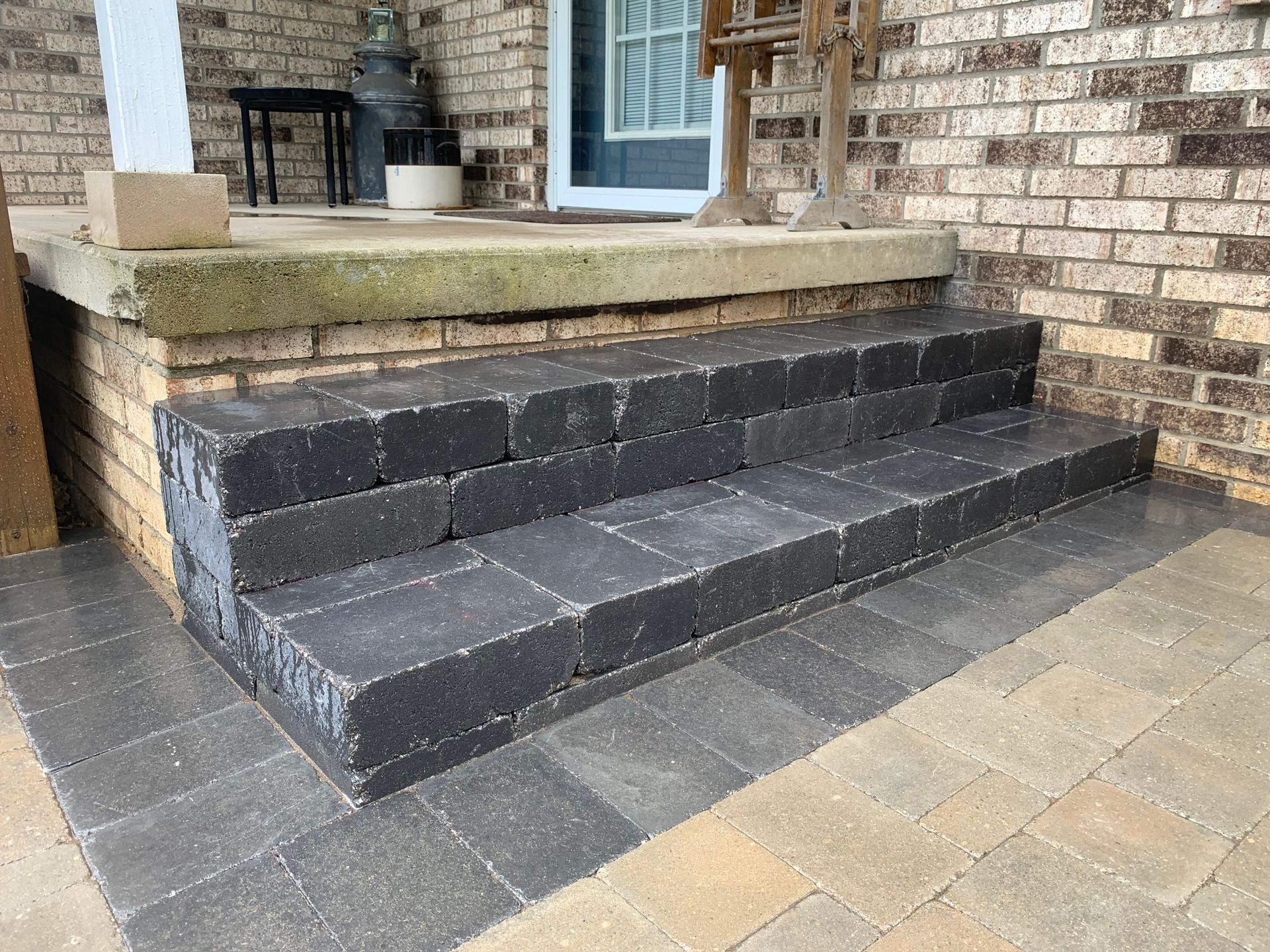 A set of steps leading up to a porch of a brick house. belgard