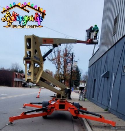 certified and trained permanent lighting professionals installing lights from an aerial lift in downtown marlette Michigan. 