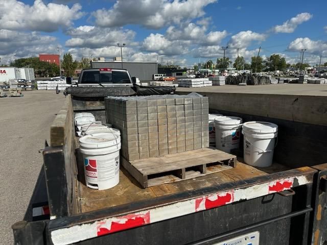 A truck with buckets and bricks in the back. brick pavers