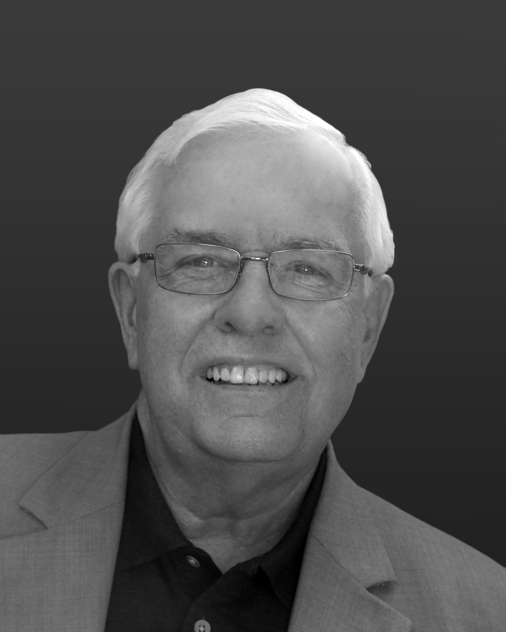 Smiling man wearing glasses and a blazer.