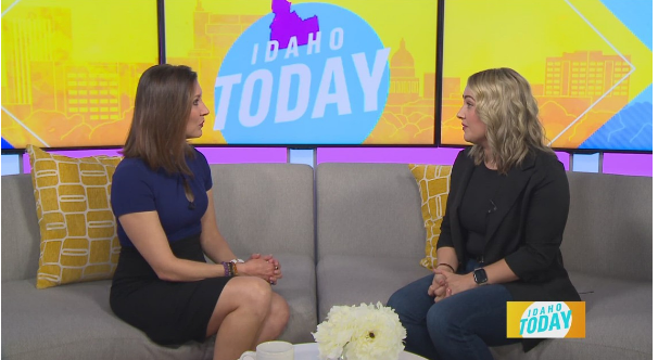 Two women are sitting on a couch in front of a screen that says idaho today