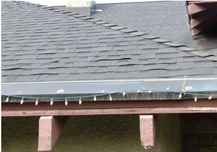 Dark asphalt shingle roof with a gutter and Christmas lights along the edge.