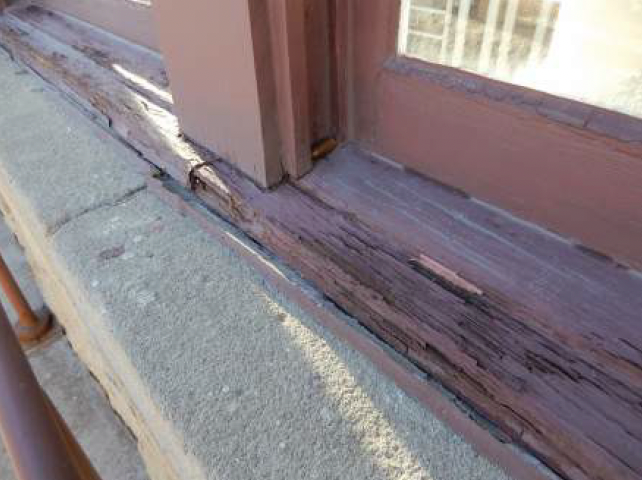 Close-up of weathered, painted wood window sill, with paint peeling and crumbling.