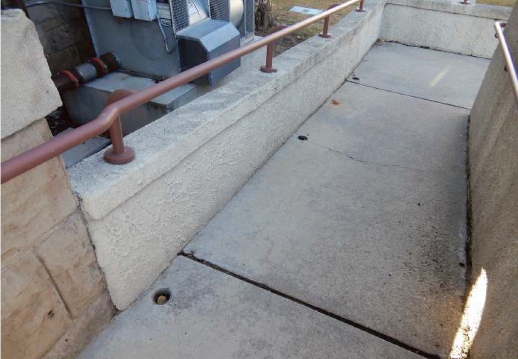 Concrete ramp with brown handrails; outdoors.