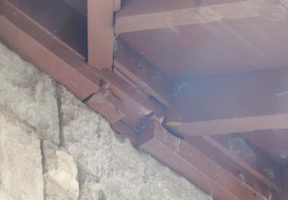 Brown wooden beams meet a light-colored stone wall.