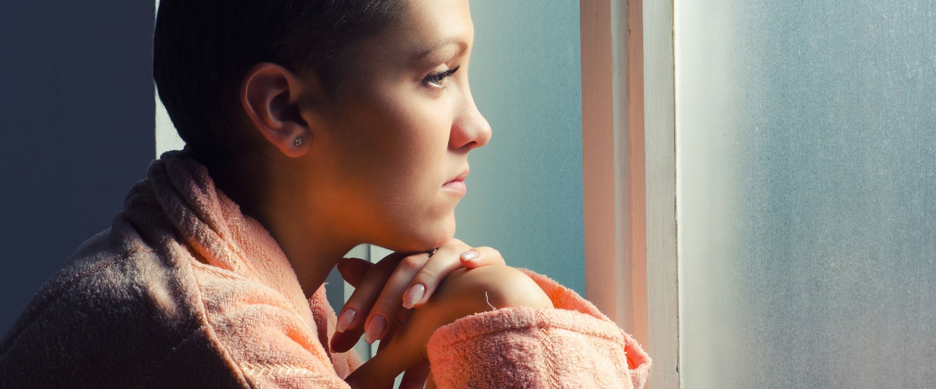 A woman with cancer is looking out of a window.