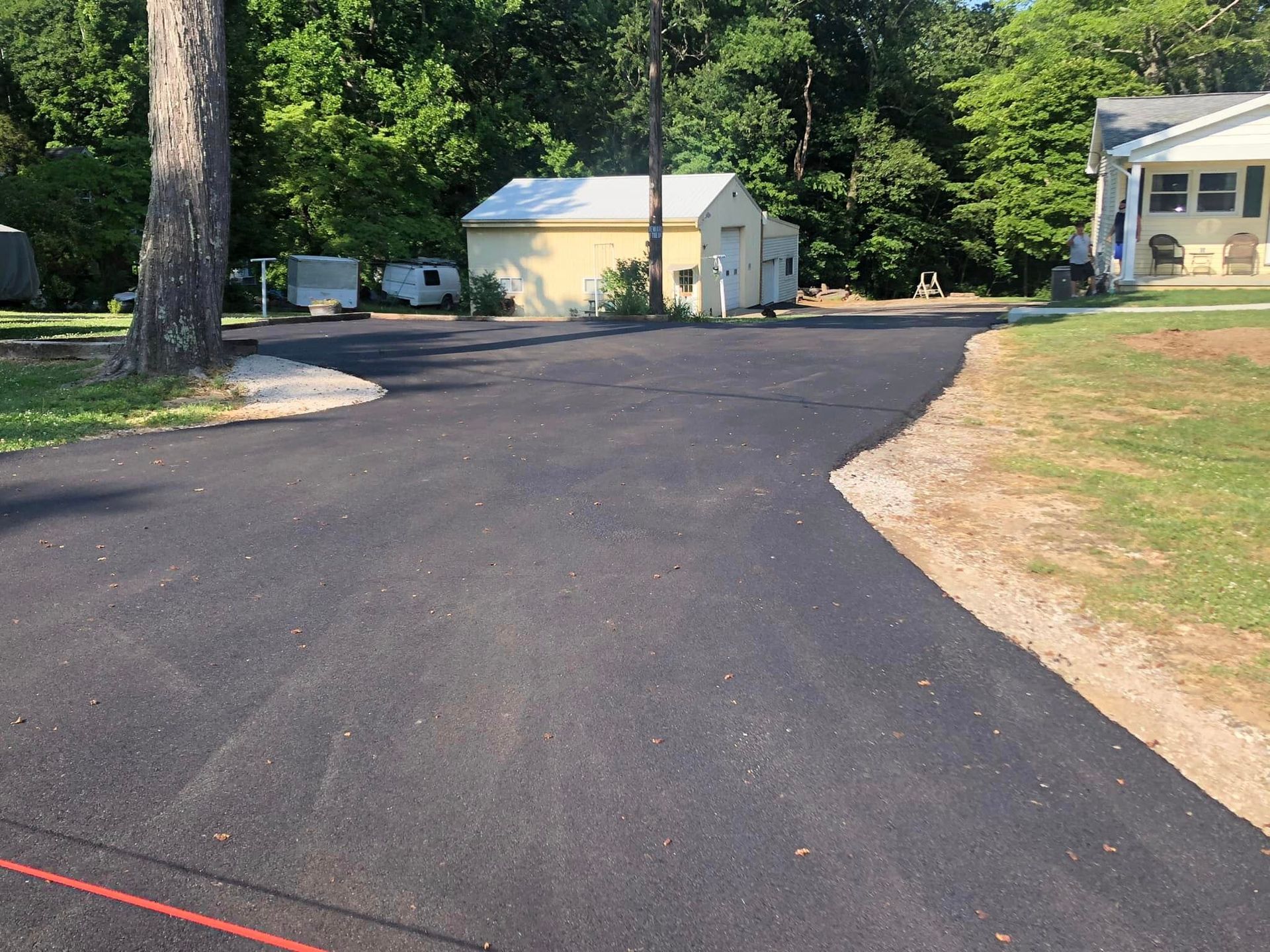 A asphalt driveway with a house in the background